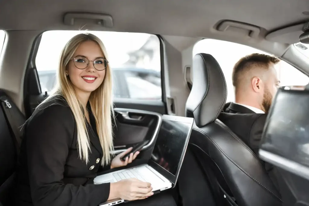 Business executive working on laptop in luxury sedan during corporate transportation from Bellingham to SeaTac