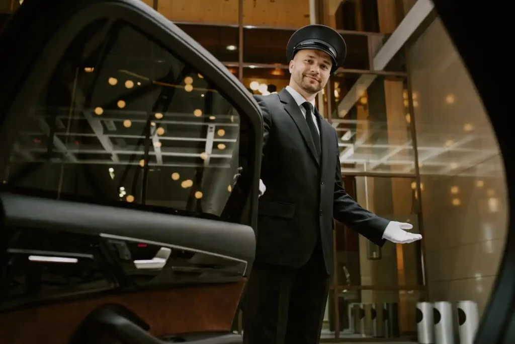 Professional chauffeur holding door of luxury town car at Medina residential pickup location