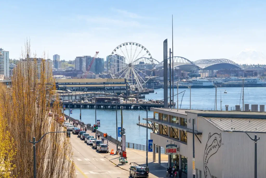 Pier 55 cruise terminal entrance on Seattle waterfront with parking lot and Great Wheel in background