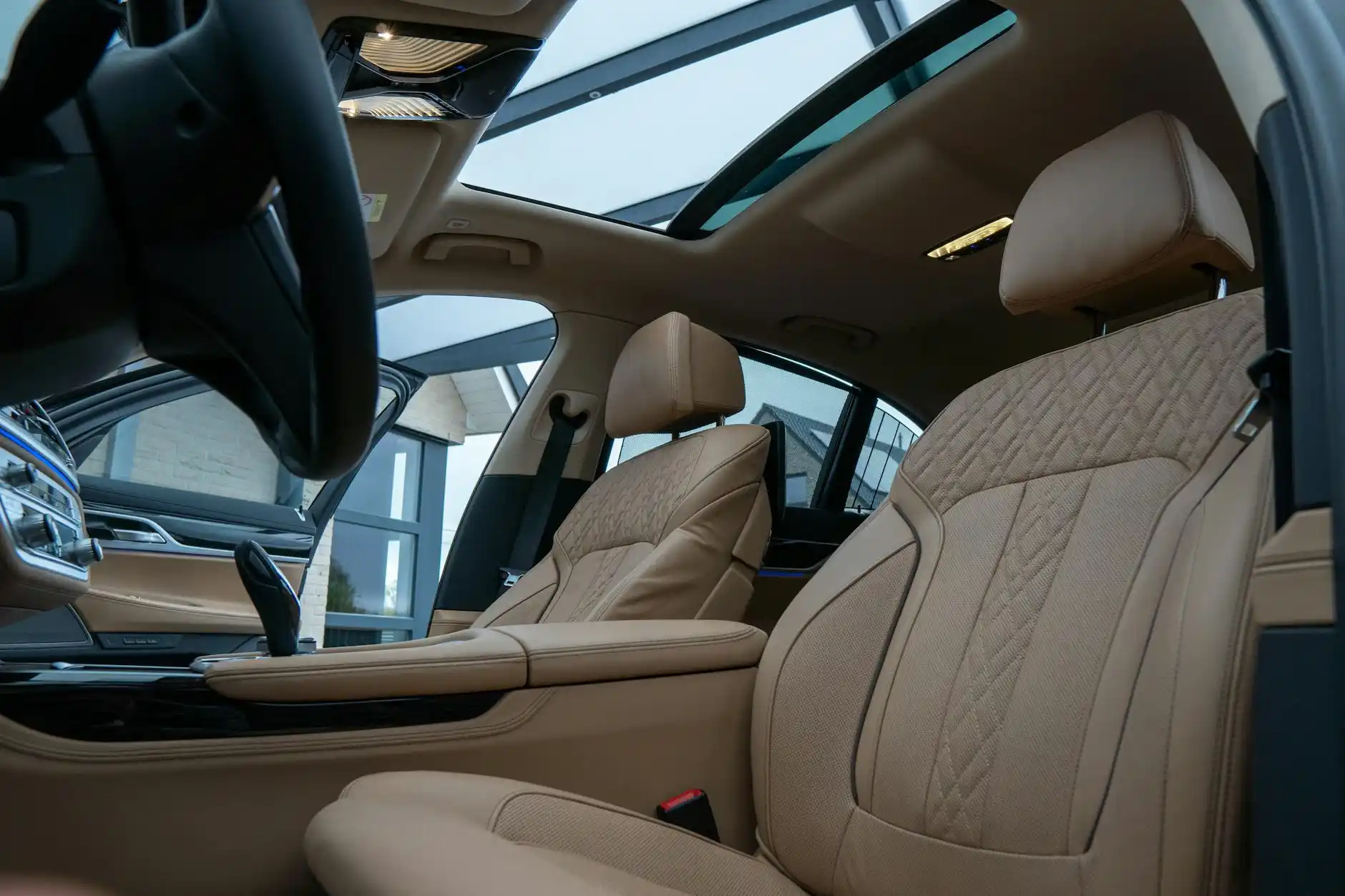 interior of a luxury SUV with leather seats, ambient lighting, and a panoramic sunroof driving through downtown Seattle skyline