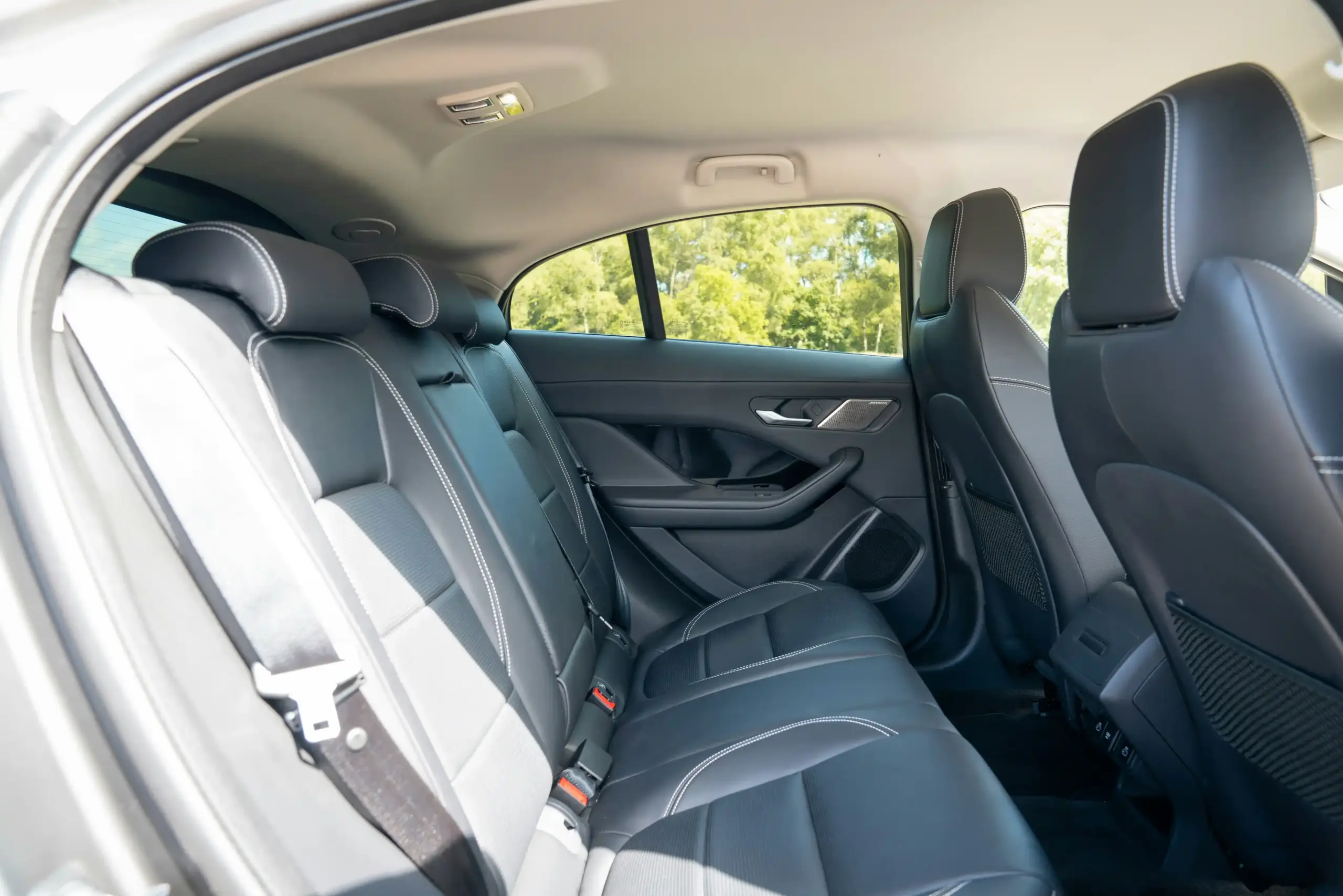 luxury town car interior with tan leather seats, bottled water, phone charging ports, and Seattle hotel district visible through rain-speckled window