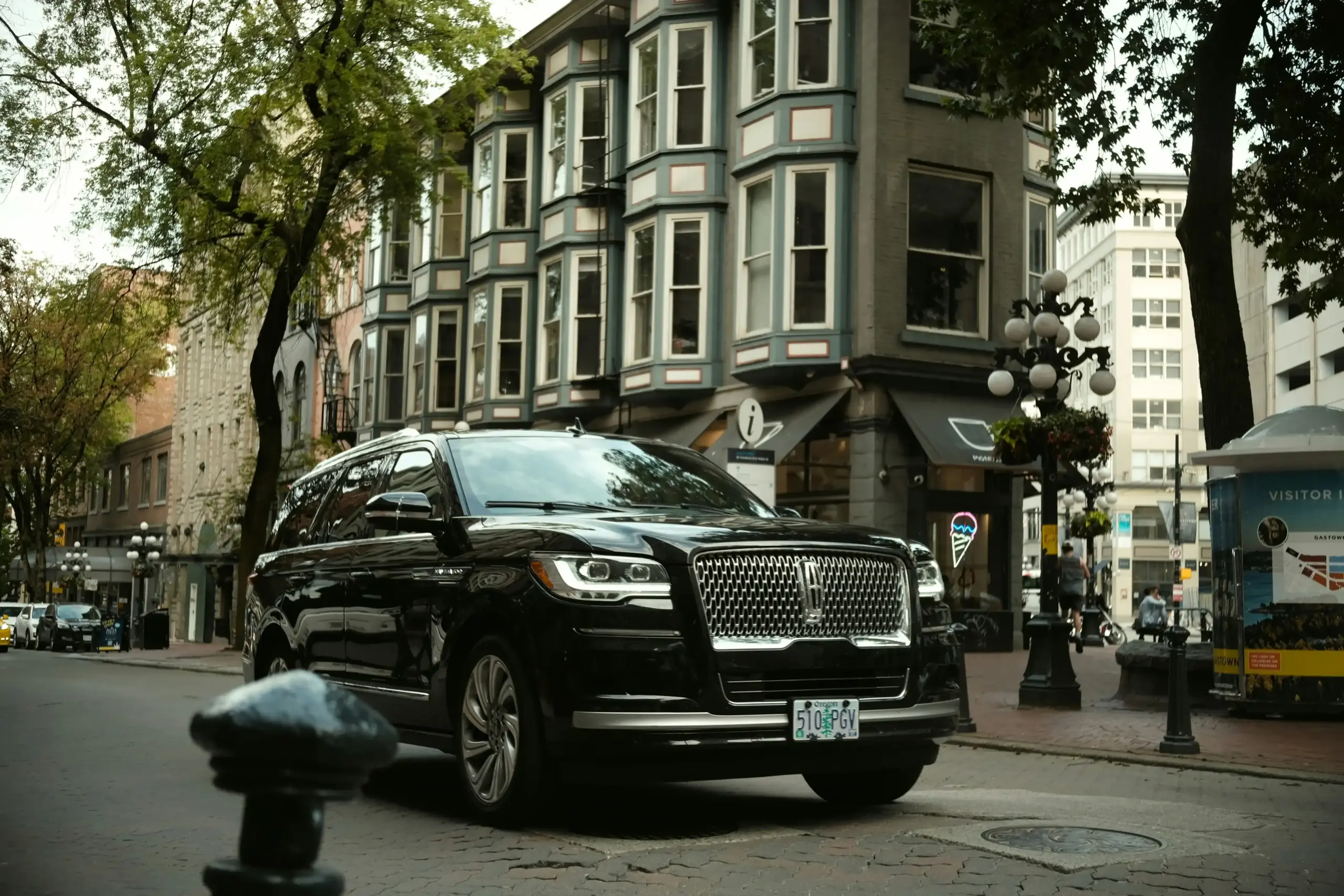 black luxury SUV parked curbside at SeaTac airport with driver assisting passengers with luggage