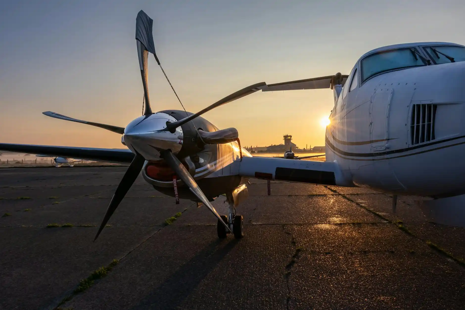 private aviation terminal entrance at Boeing Field with a polished executive sedan and luxury SUV lined up curbside on a rainy Seattle morning, reflecting city lights on the pav...