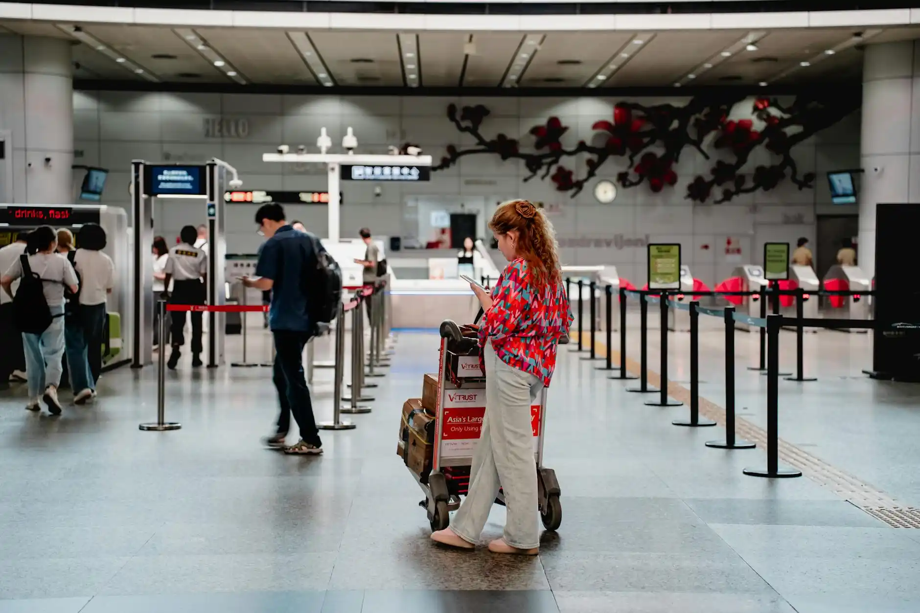 Seattle Tacoma International Airport baggage claim area with carousel signs, chauffeur in dark suit beside a polished luggage cart, arriving family with carry-ons and checked bags