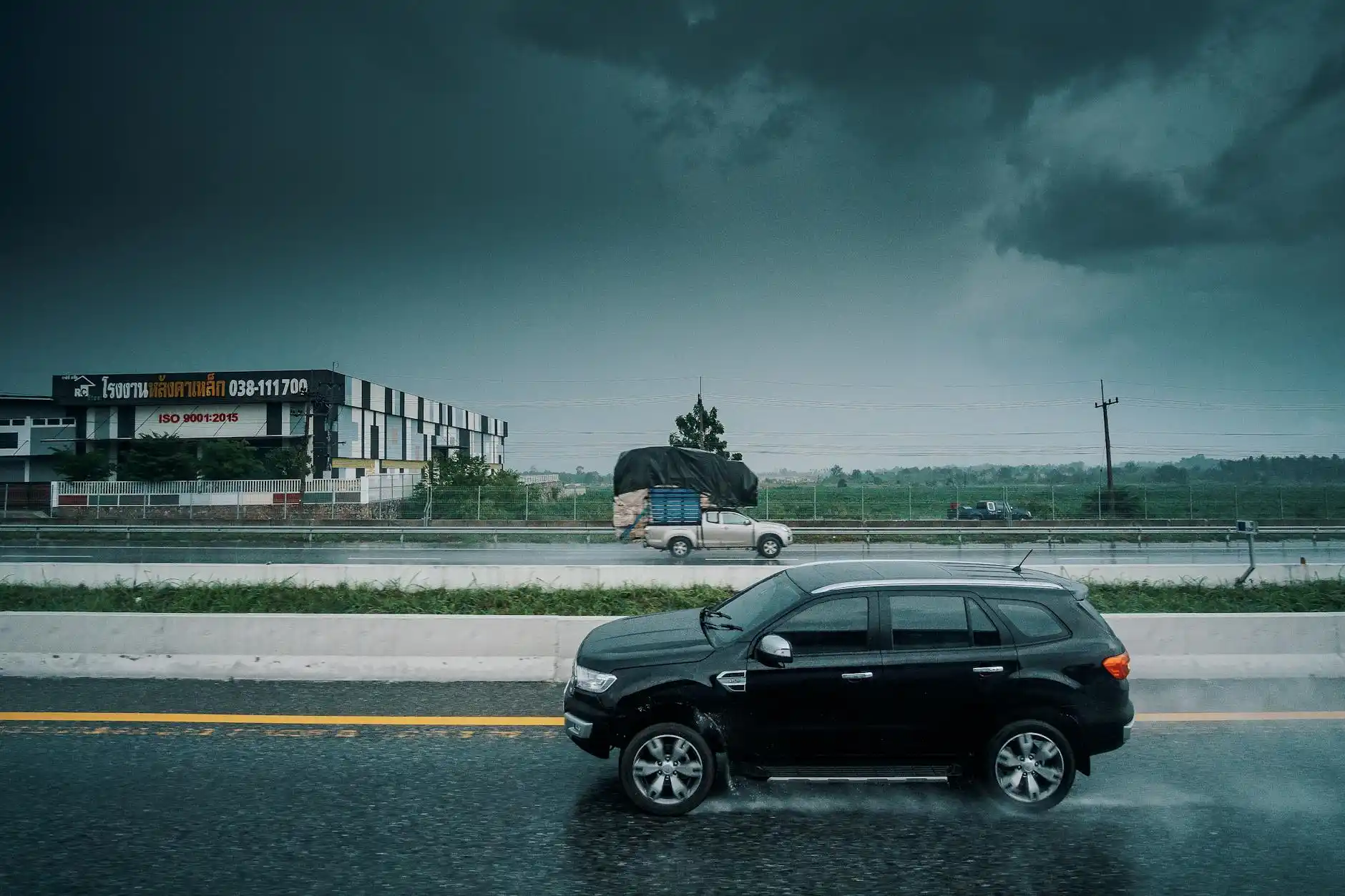 luxury black SUV parked in commercial pickup area at SeaTac airport during light rain, chauffeur loading suitcases, Seattle skyline mood and Pacific Northwest atmosphere
