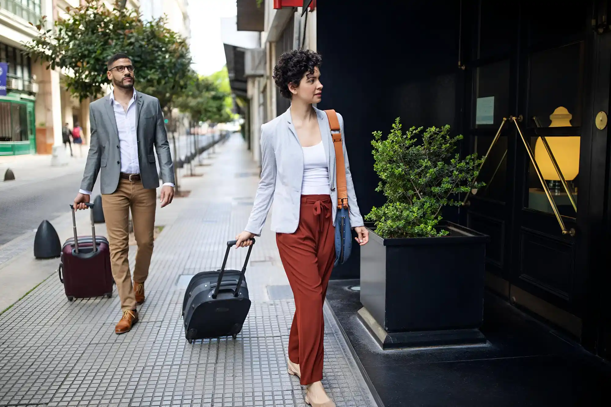 upscale Seattle hotel entrance with bellhop cart, cruise passengers in smart casual clothing, stacked suitcases, and a waiting executive town car in light rain