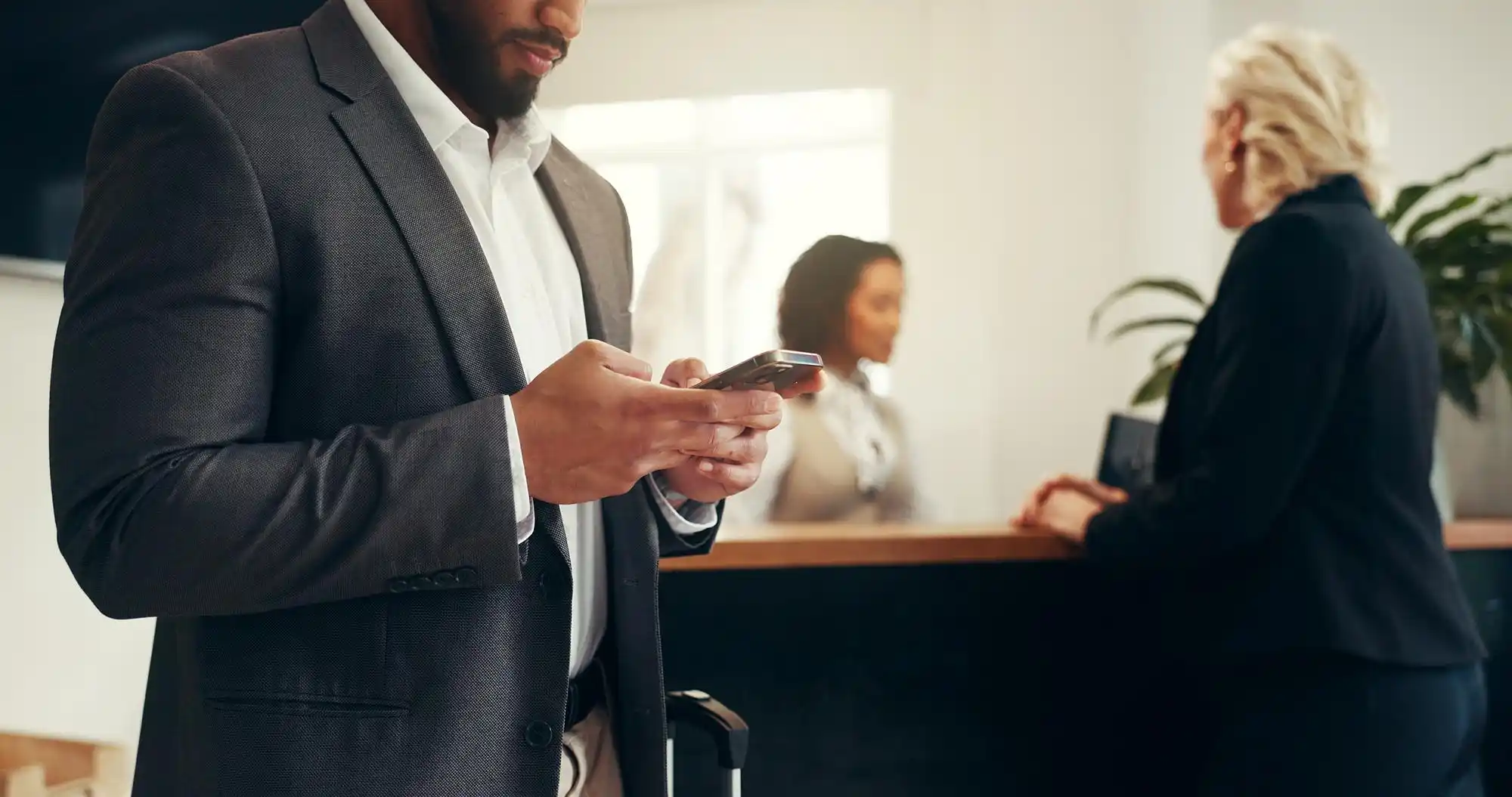 traveler at hotel desk reviewing cruise documents and smartphone booking confirmation for Seattle port transfer, coffee cup and luggage nearby
