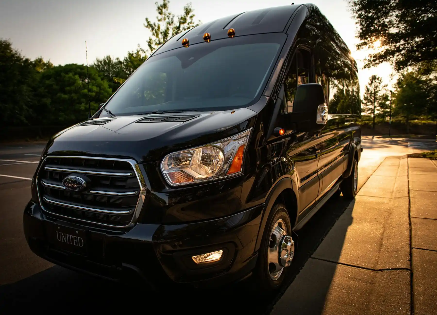 luxury black sprinter van parked with Seattle skyline in background during golden hour, travelers loading luggage