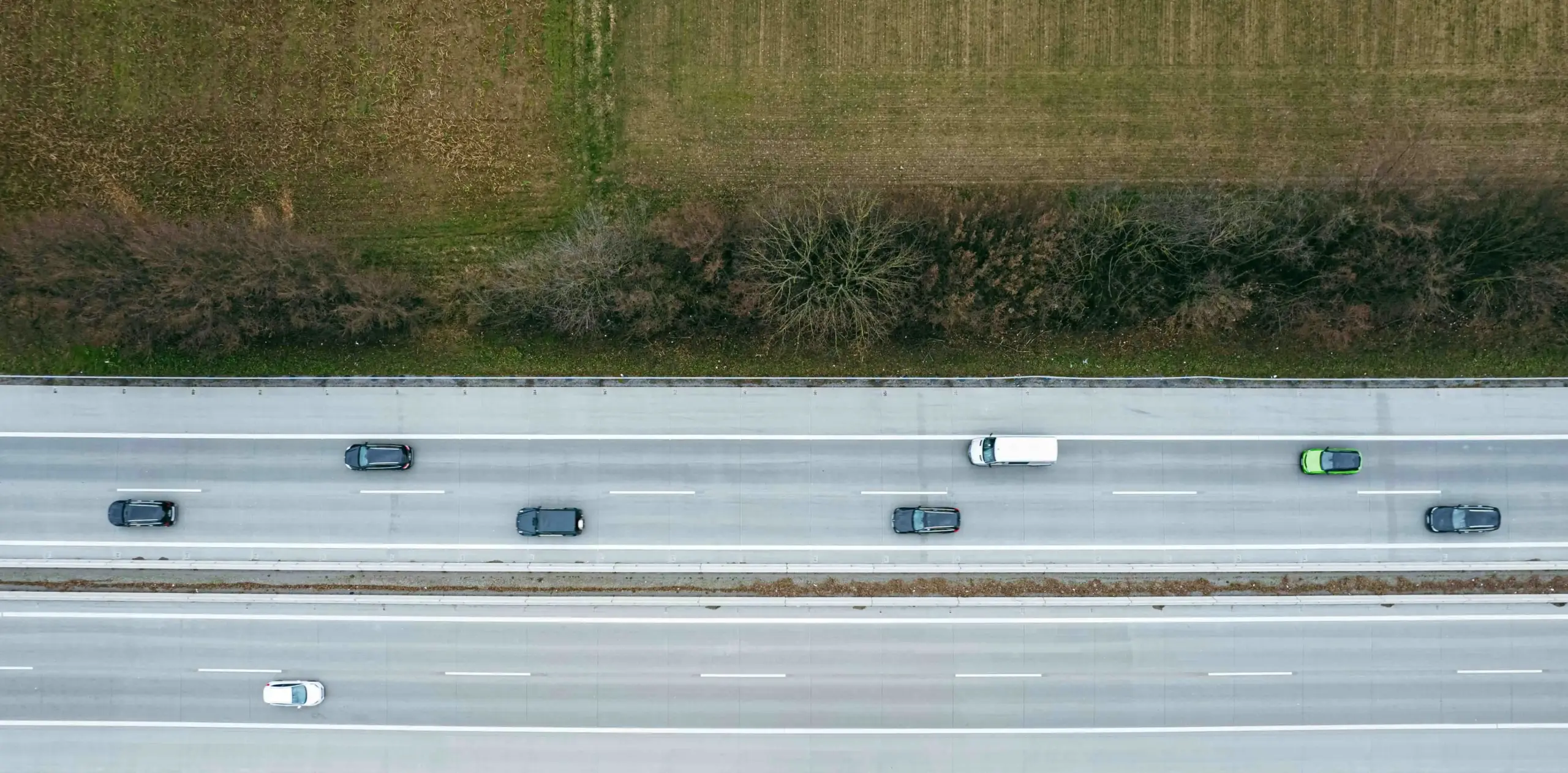 aerial-style road travel scene of Interstate 5 near the US-Canada border, luxury passenger van heading north, evergreen trees, blue highway signs, distant border crossing lanes