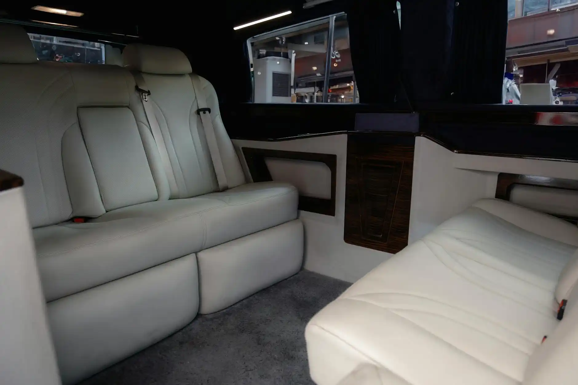 upscale interior of a black Sprinter van with leather captain seats, soft ambient lighting, large windows, carry-on luggage stored neatly, passengers relaxing during road trip