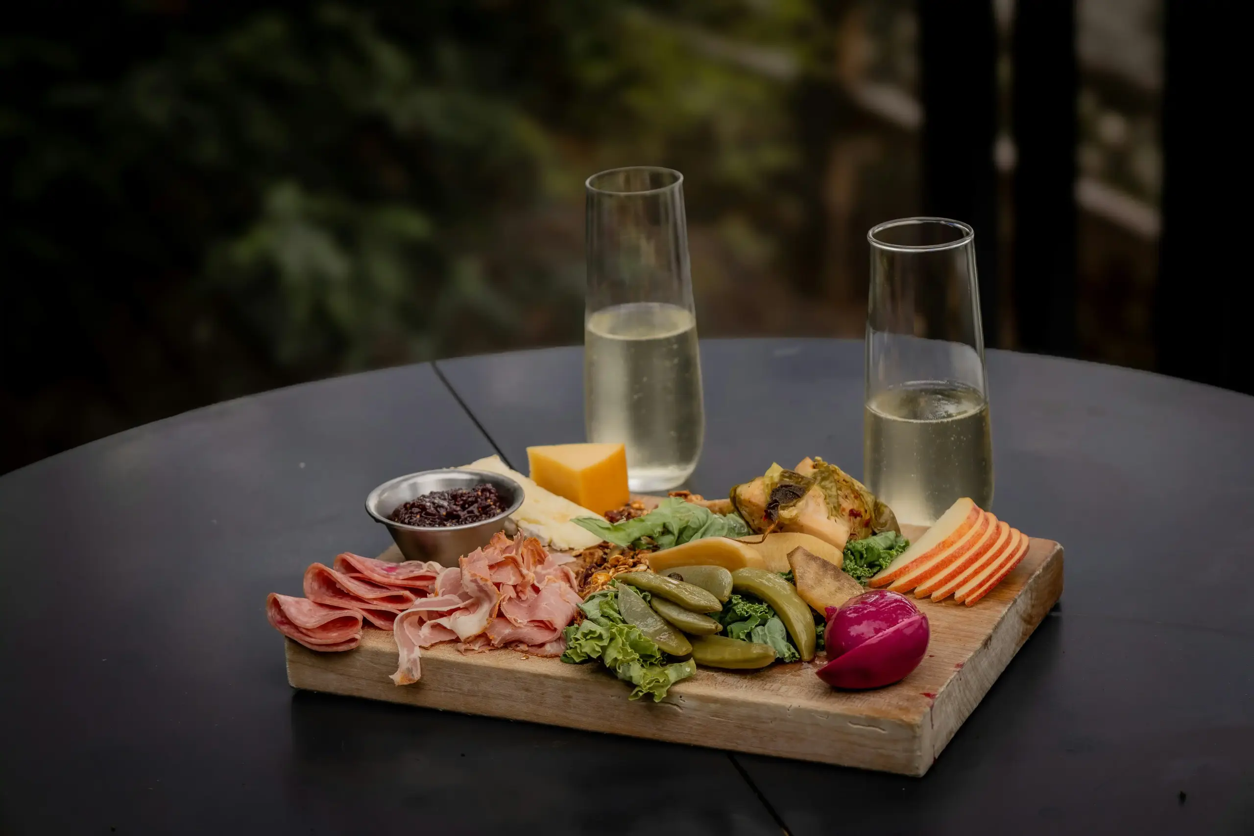 beautifully plated lunch at a winery patio with wine glasses, charcuterie board, and vineyard view in the background