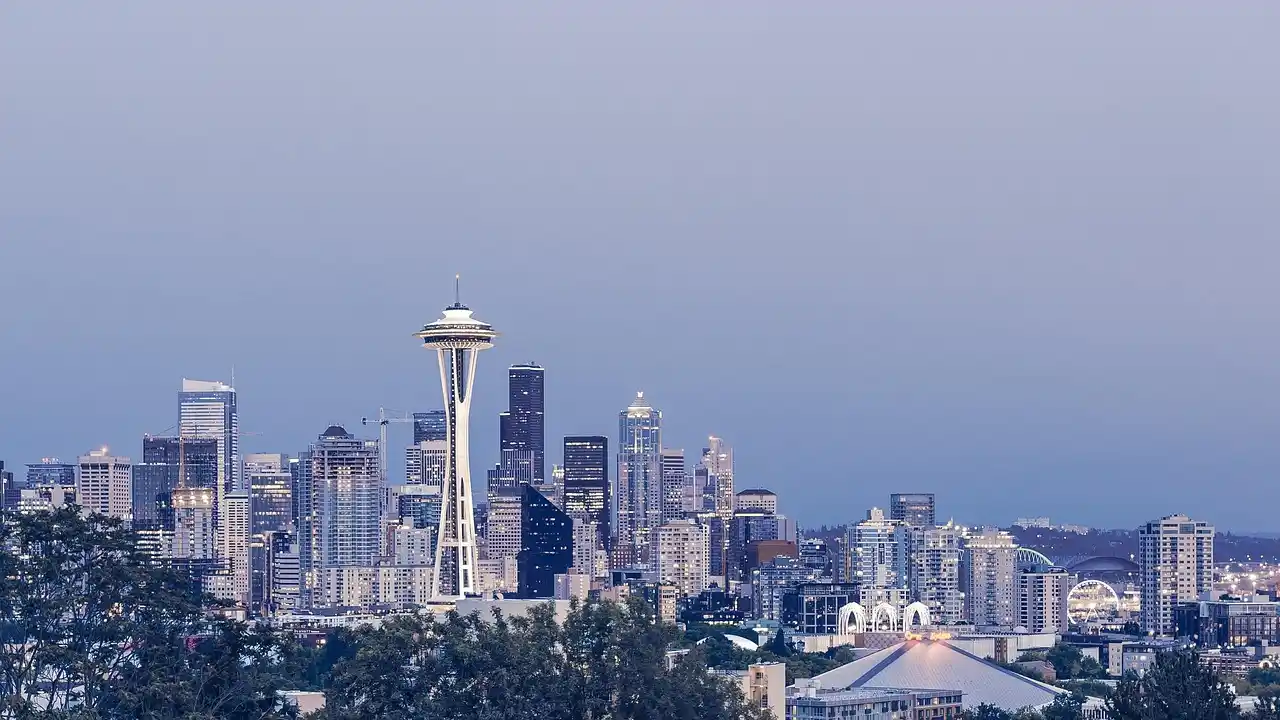 elegant black town car and full-size luxury SUV side by side outside a downtown Seattle hotel, doorman assisting travelers with luggage, evening city lights
