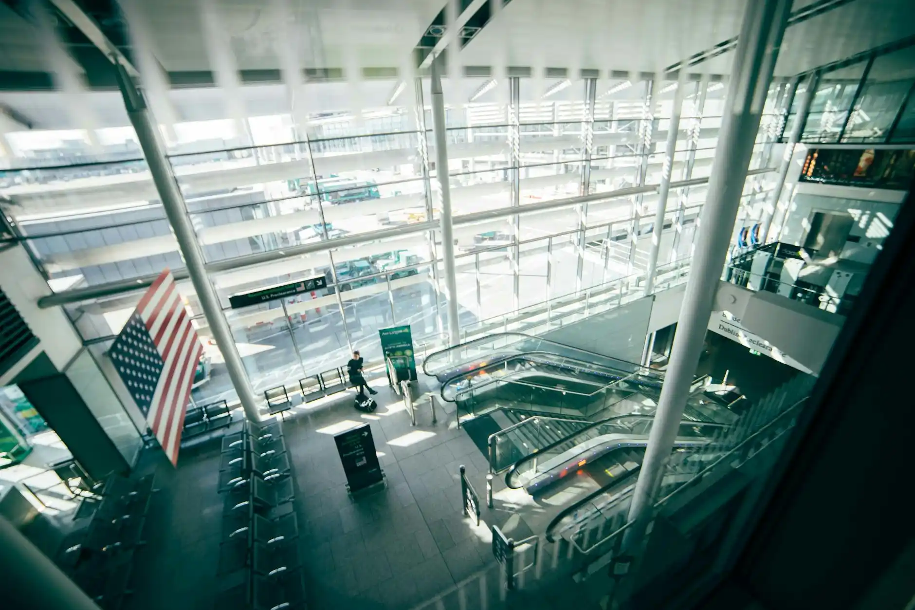 chauffeur loading suitcases into a luxury SUV at SeaTac airport arrivals, travelers in smart casual clothing, terminal glass facade, realistic rainy Seattle setting