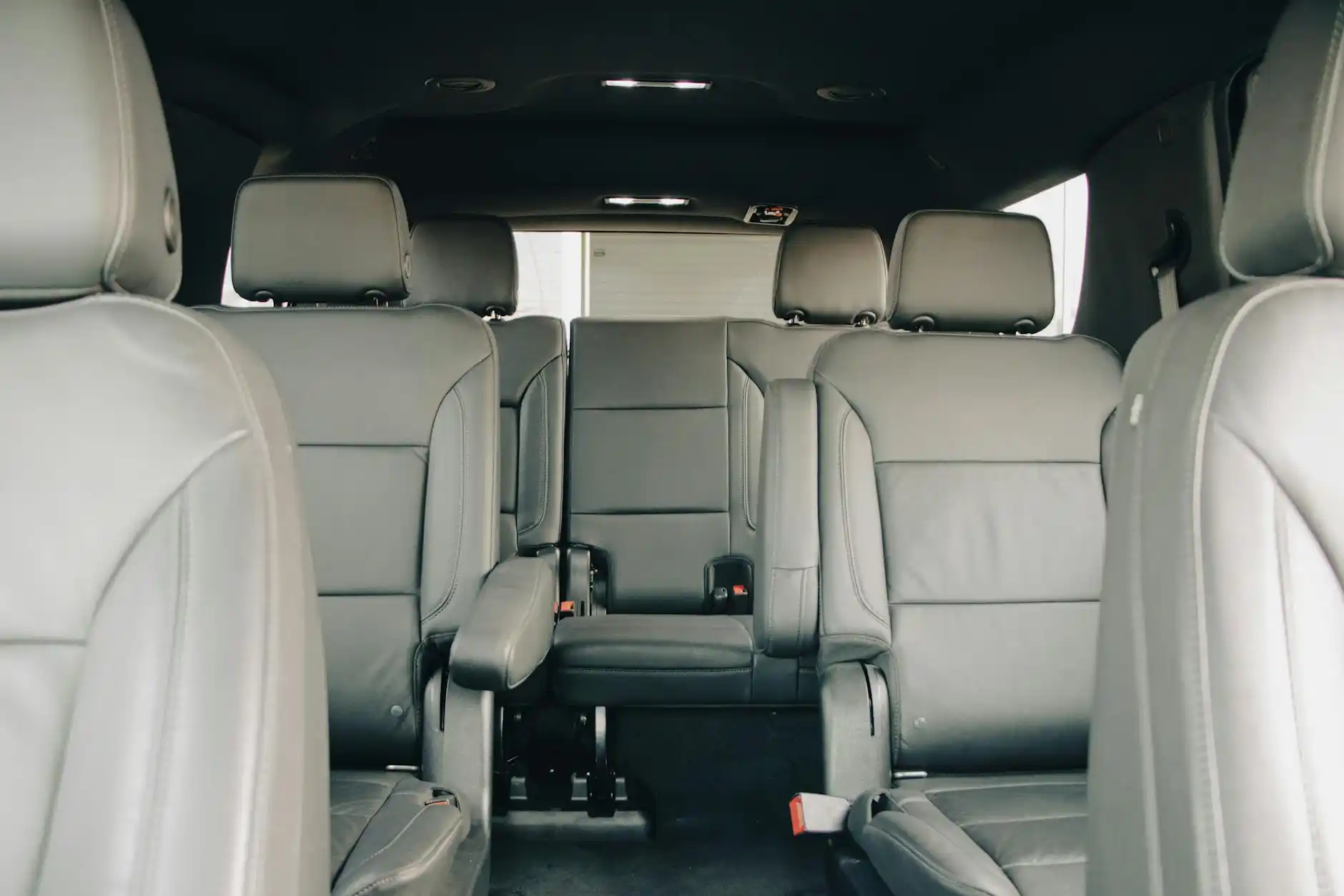 interior of a spacious executive shuttle with leather captain seats, wide aisle, tinted windows, and overhead lighting as a group of business travelers rides through downtown Se...