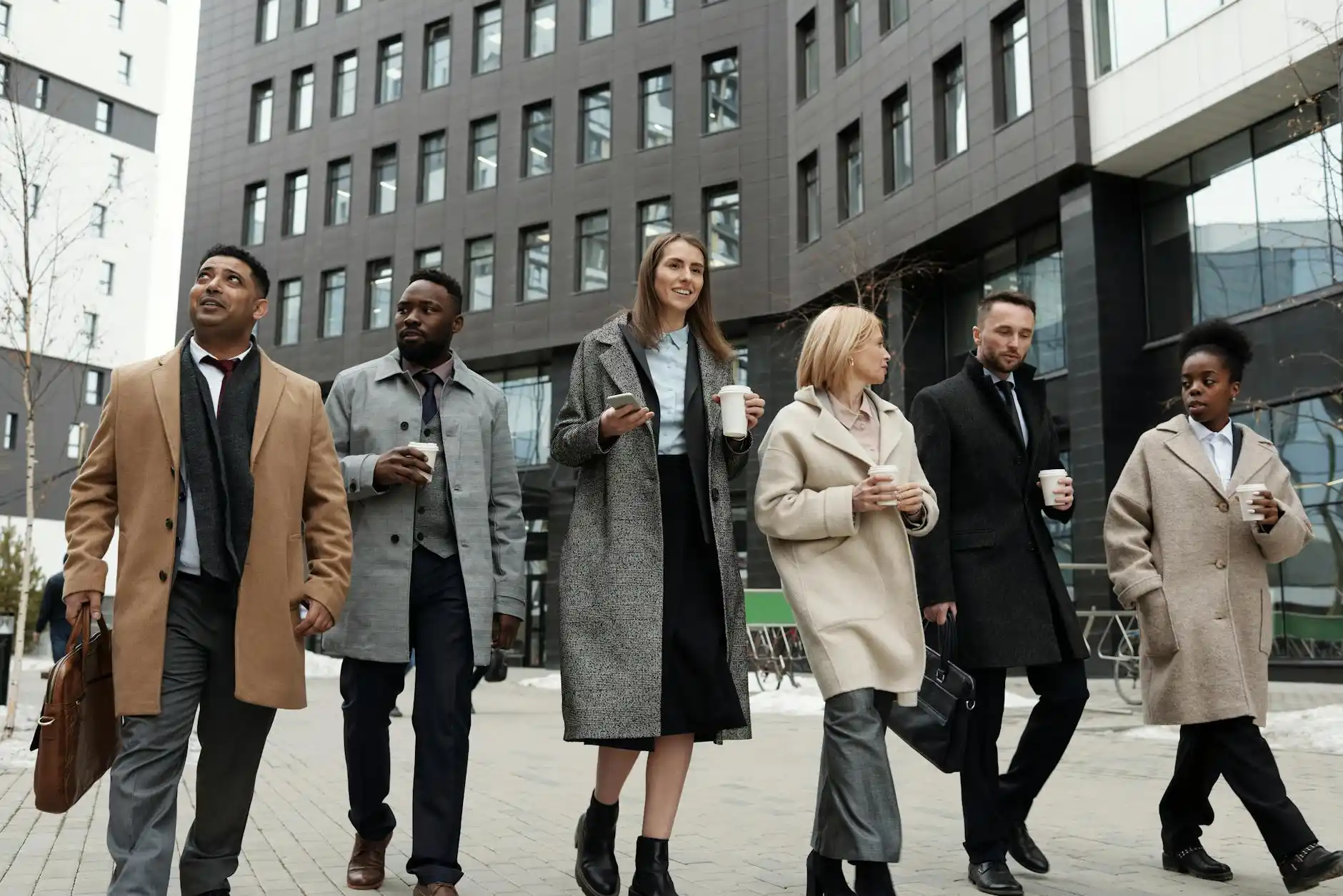 corporate conference attendees with name badges entering a luxury shuttle outside a glass office tower in downtown Seattle during early morning light
