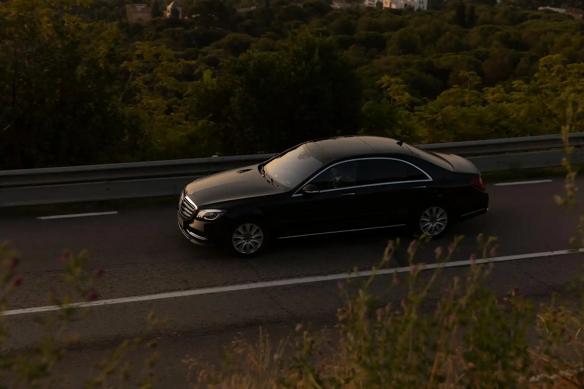 luxury sedan driving north on Interstate 5 with evergreen trees, overcast Pacific Northwest sky, visible road sign toward Vancouver BC and border crossing