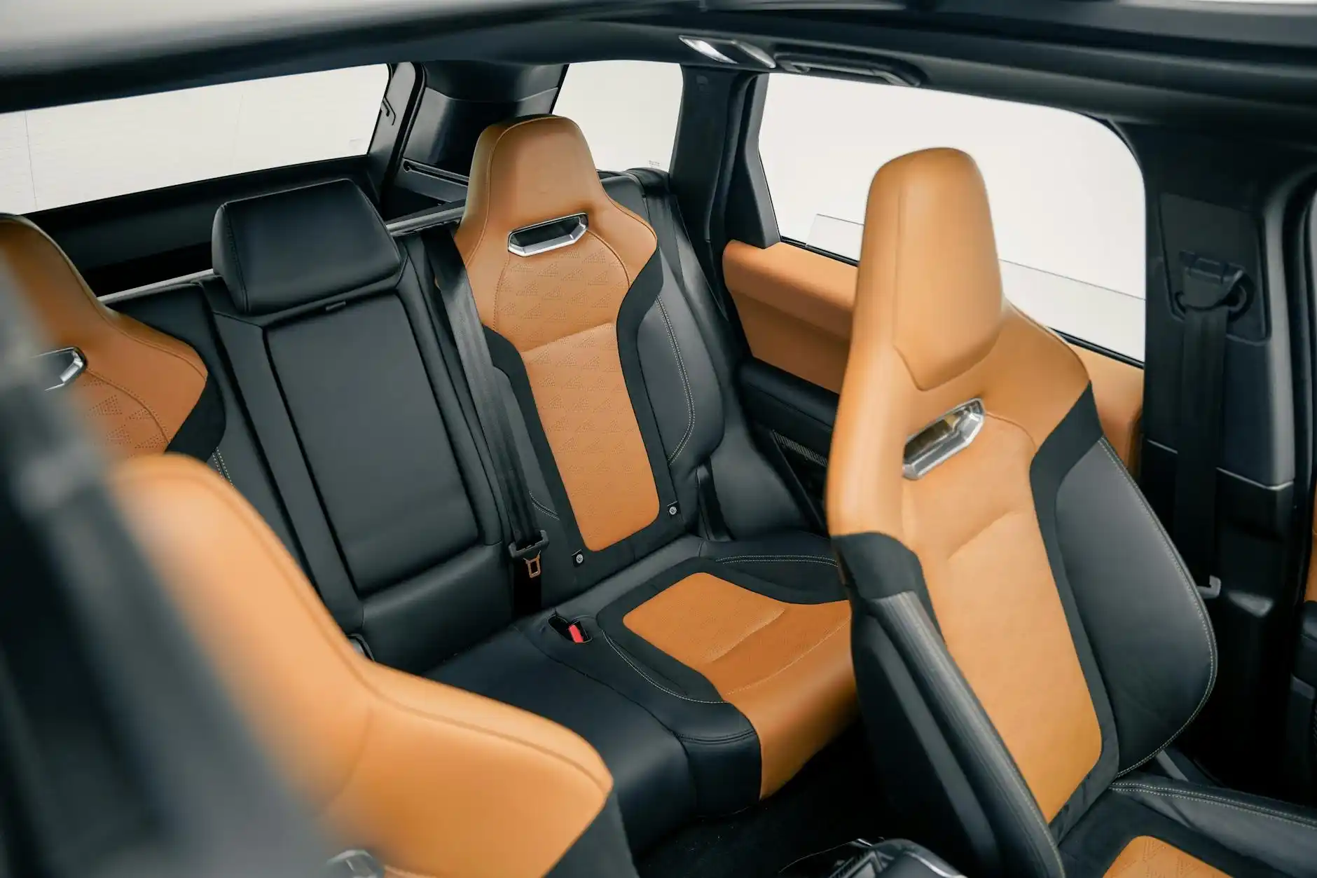 interior of premium black SUV with tan leather seats, bottled water, phone charging ports, and neatly arranged suitcases in rear cargo area