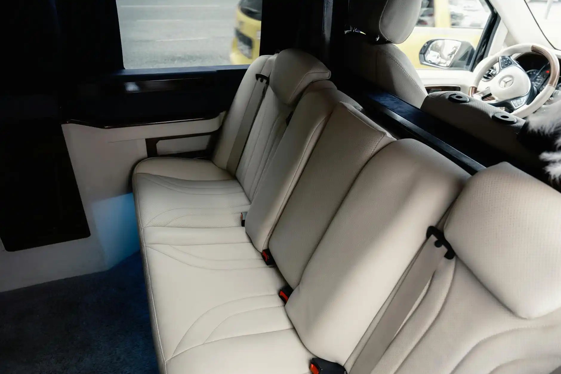 spacious black Sprinter van interior with leather captain seats, ski bags secured in rear cargo area, snowy mountain lodge visible through windows