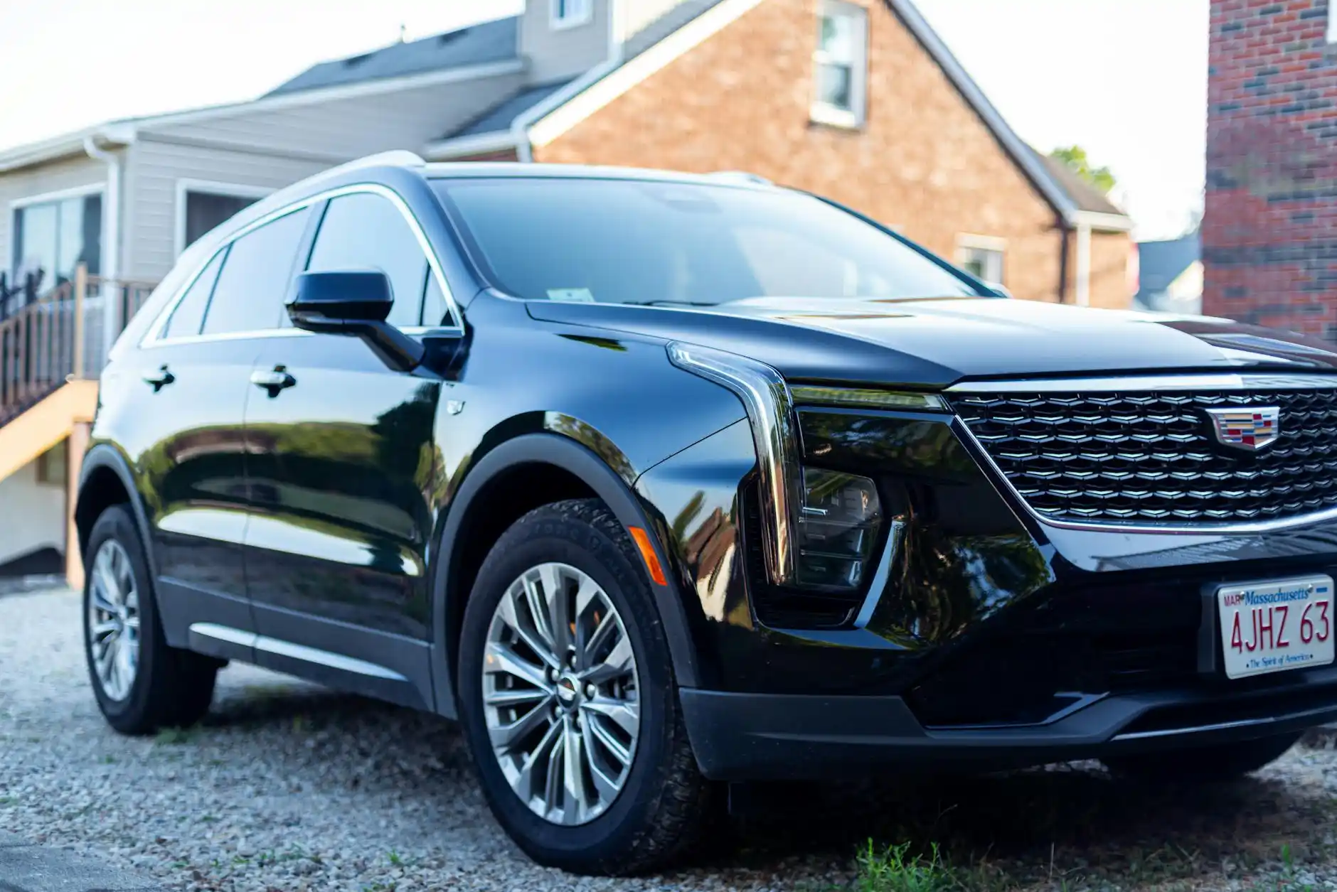 luxury black SUV parked outside a picturesque Woodinville winery with vineyard rows, golden afternoon light, and elegantly dressed wine tourists preparing to depart