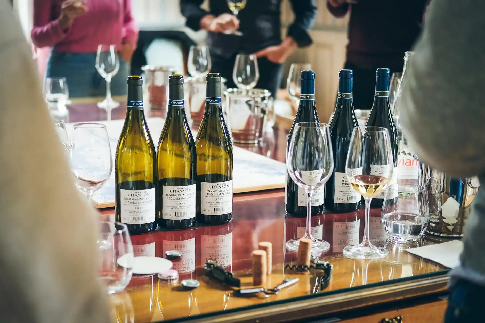 stylish group of friends at a boutique Woodinville tasting room, wine glasses in hand, rustic wood interiors, soft natural light, and bottles displayed behind the bar