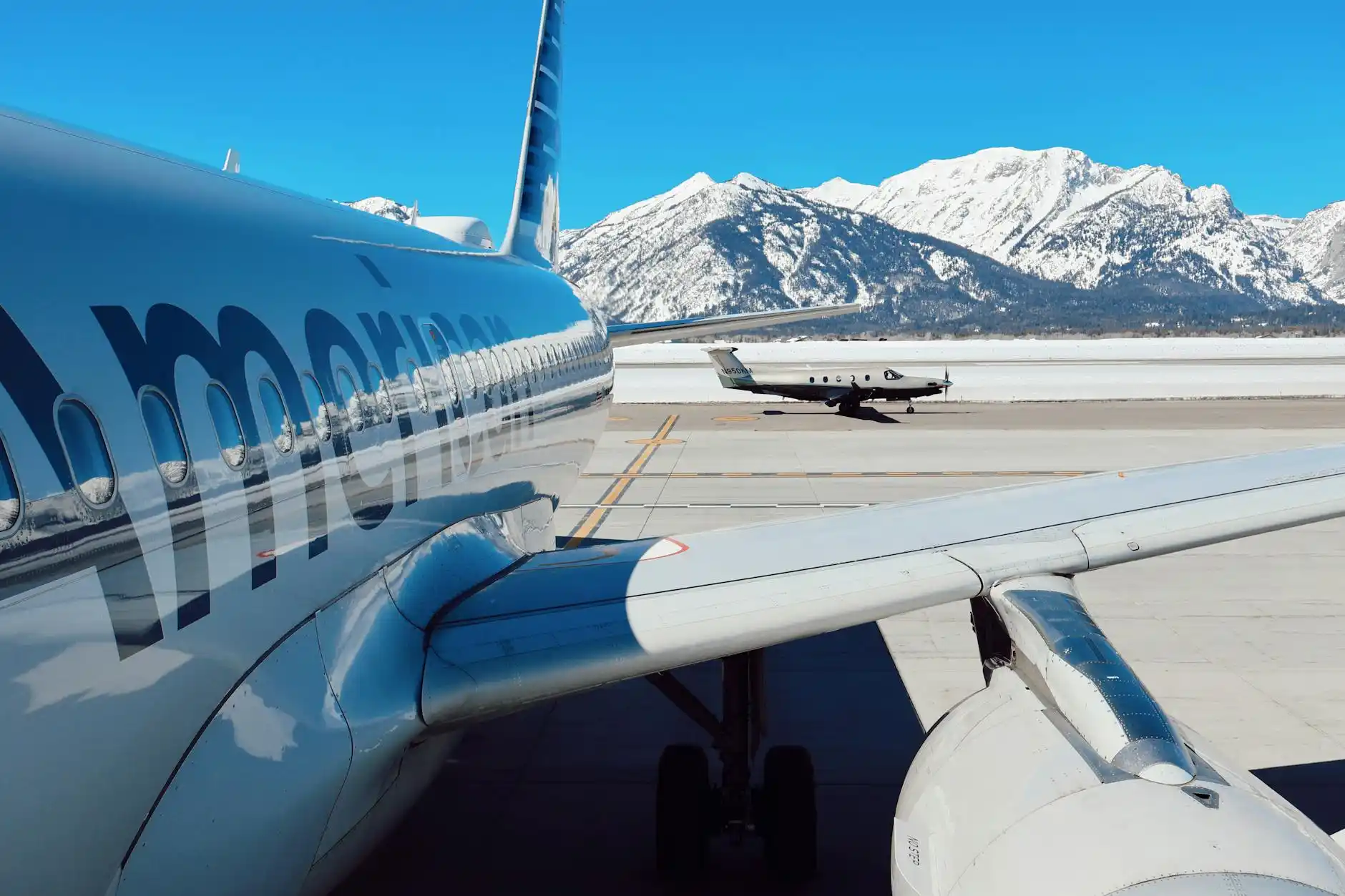 airport porter-style assistance scene with chauffeur loading multiple suitcases into a luxury SUV for a family outside Sea-Tac terminal, mountains faintly visible in background