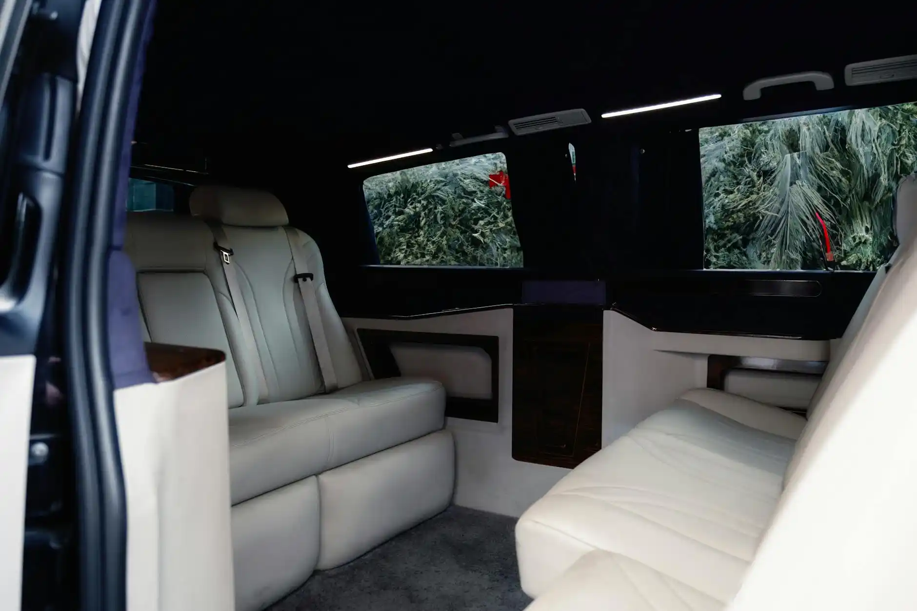 luxury Mercedes-style passenger van interior with leather seating, ambient lighting, bottled water, and wine country passengers departing for a Woodinville tasting tour
