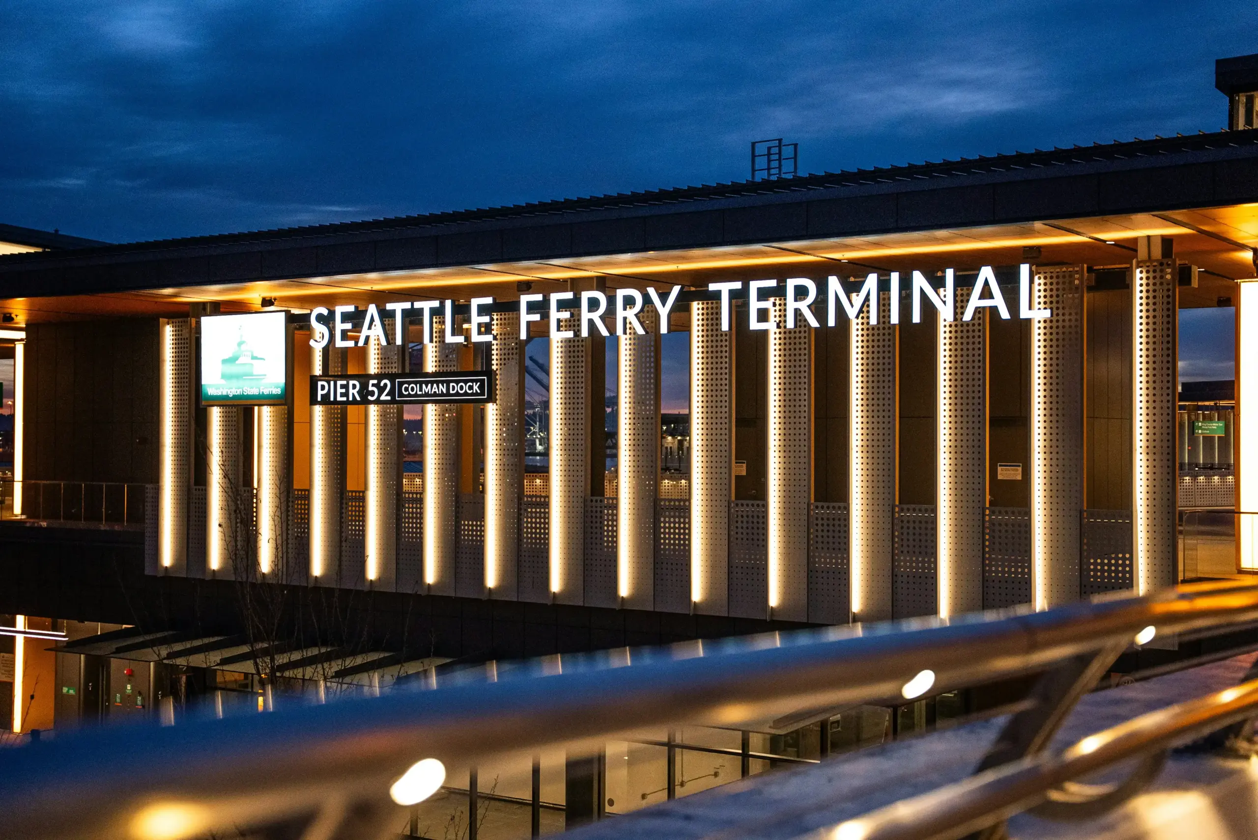 family with children and stacked luggage arriving on time at Anacortes ferry terminal from a private vehicle, waterfront terminal signs and ferry in background