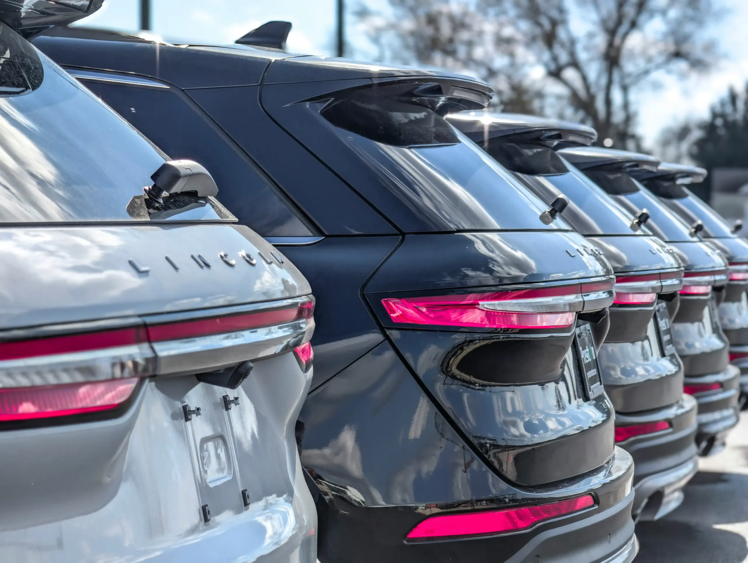 lineup of premium black SUVs including full-size luxury models and midsize executive crossovers in a polished private transportation lot, Seattle skyline faintly visible in back...