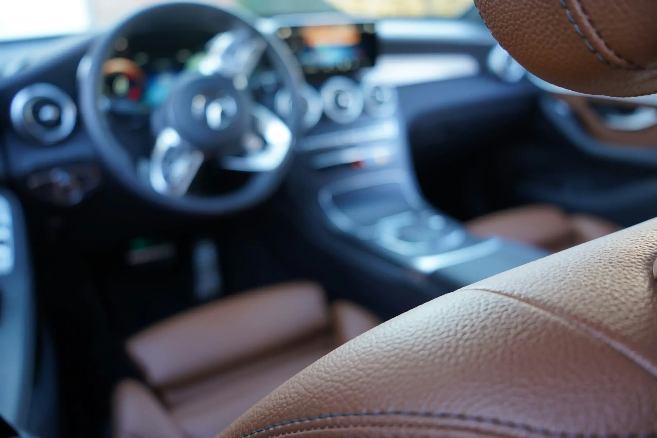 elegant luxury SUV interior with tan leather captain seats, panoramic roof, soft ambient lighting, bottled water and phone charging ports ready for executive passengers
