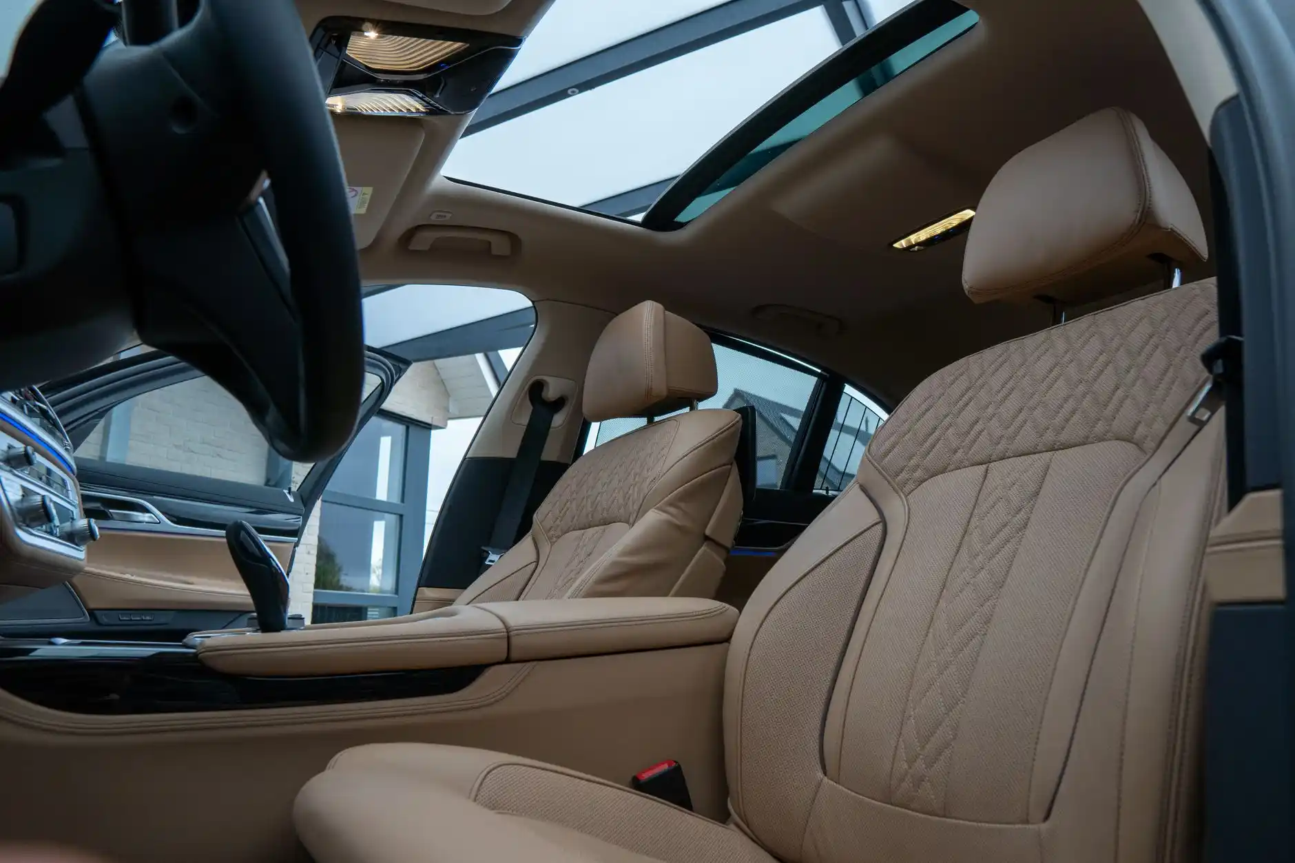 luxury black SUV interior with leather seats, neatly stored luggage, bottled water in cup holder, rainy Seattle airport roadway visible through window