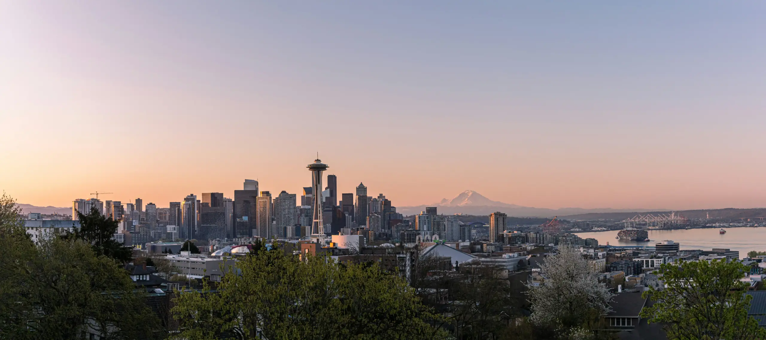 luxury black SUV parked outside a downtown Seattle hotel entrance at sunrise, chauffeur opening the rear passenger door, travelers with rolling luggage, city skyline softly visi...