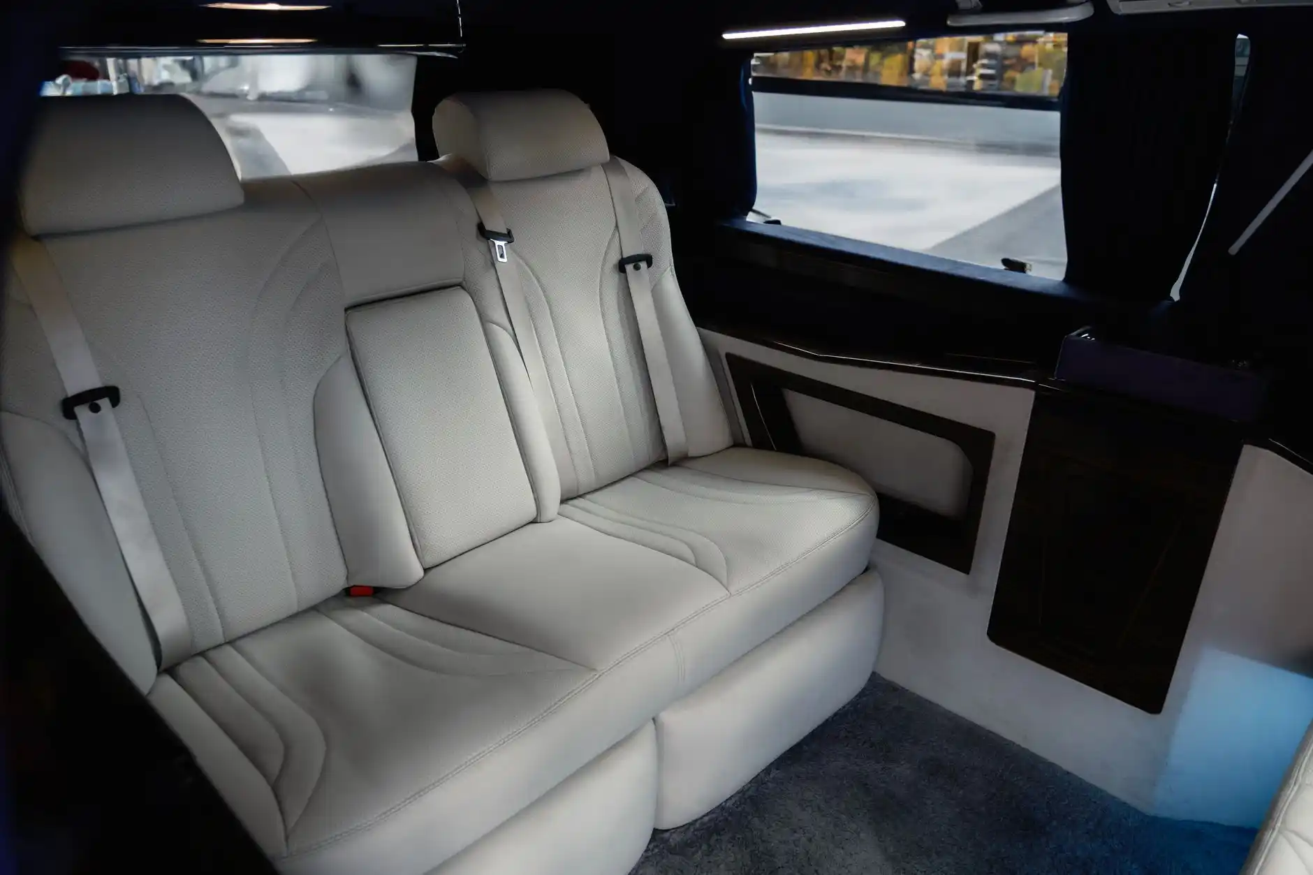 interior of a premium Sprinter van with leather captain chairs, overhead lighting, and stacked ski bags neatly loaded in rear cargo area