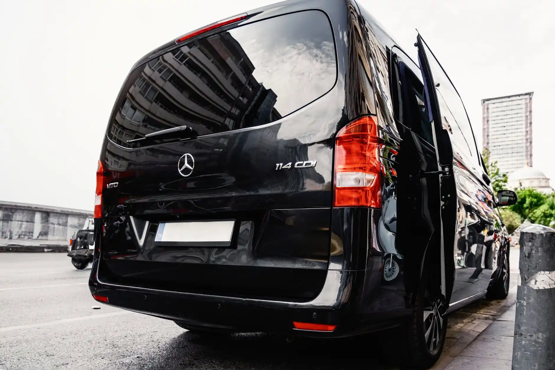 chauffeur opening the sliding door of a luxury van in front of a modern Bellevue home, early morning light, neatly dressed group holding tasting itinerary and coffee cups