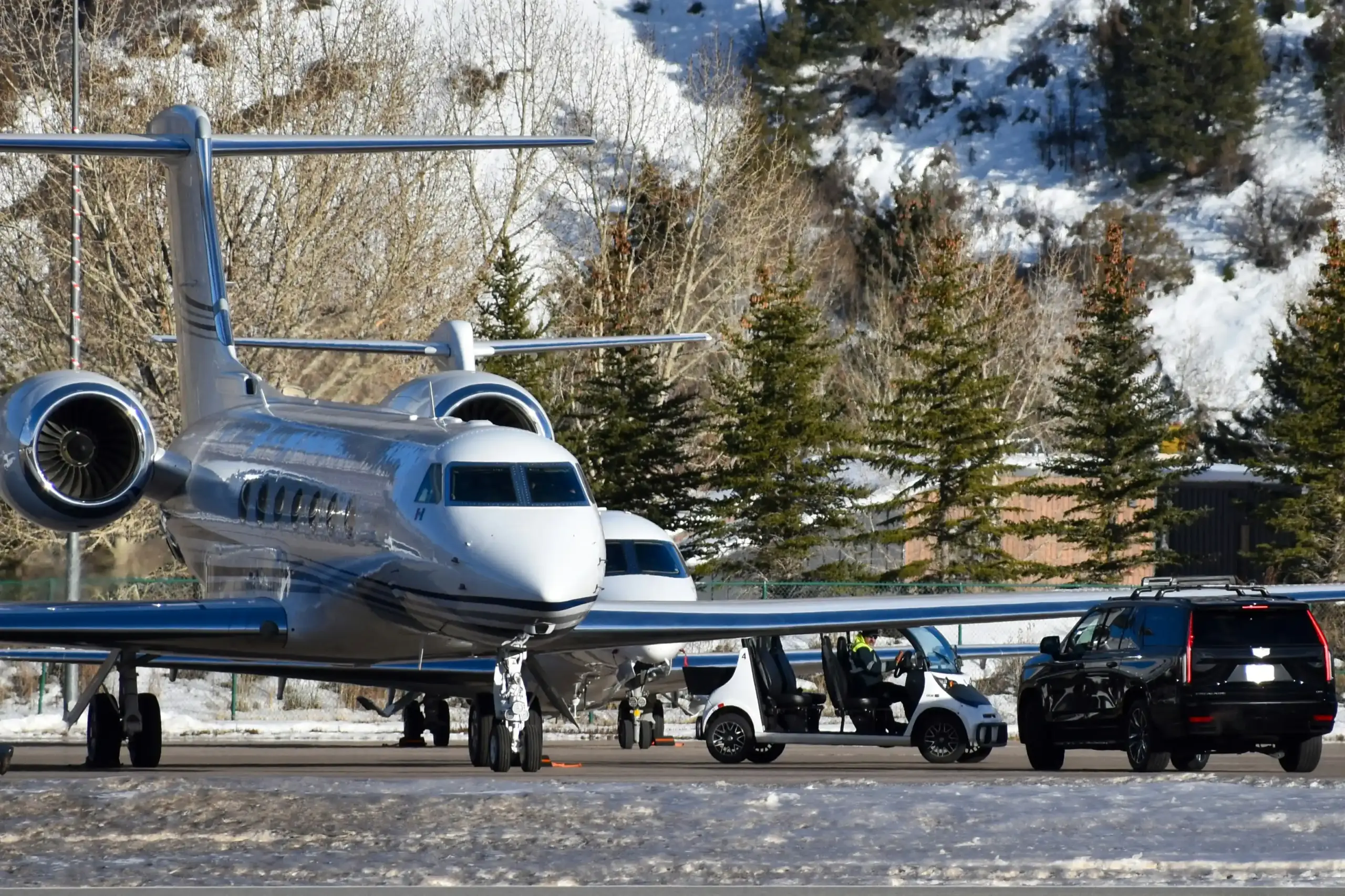 black premium SUV staged outside a Seattle-area FBO with a private jet on the ramp, driver standing by with discreet luggage assistance, overcast Pacific Northwest light