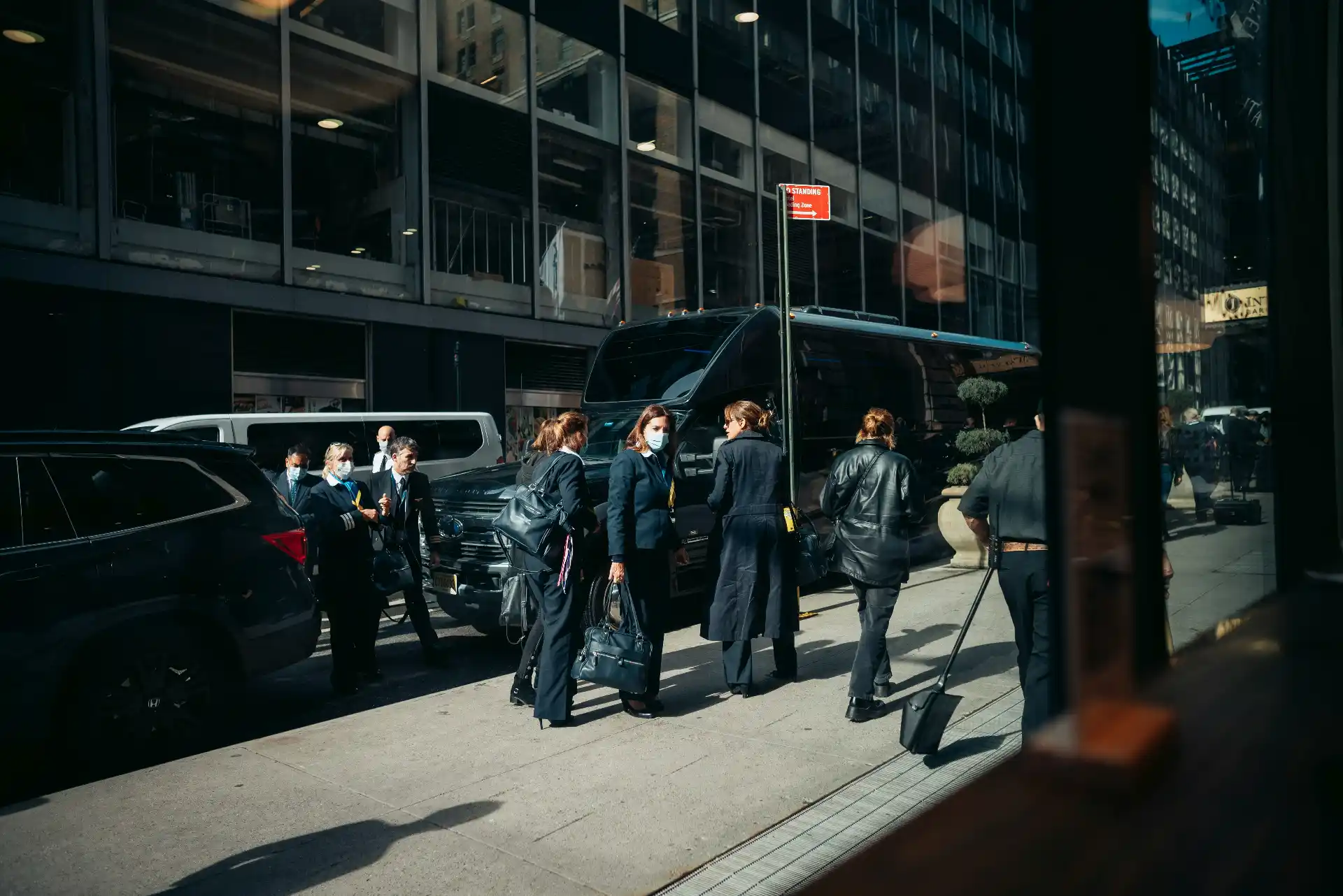 Executive shuttle van collecting business travelers outside a modern downtown Seattle office, with the Space Needle visible in the distance, professional documentary photography
