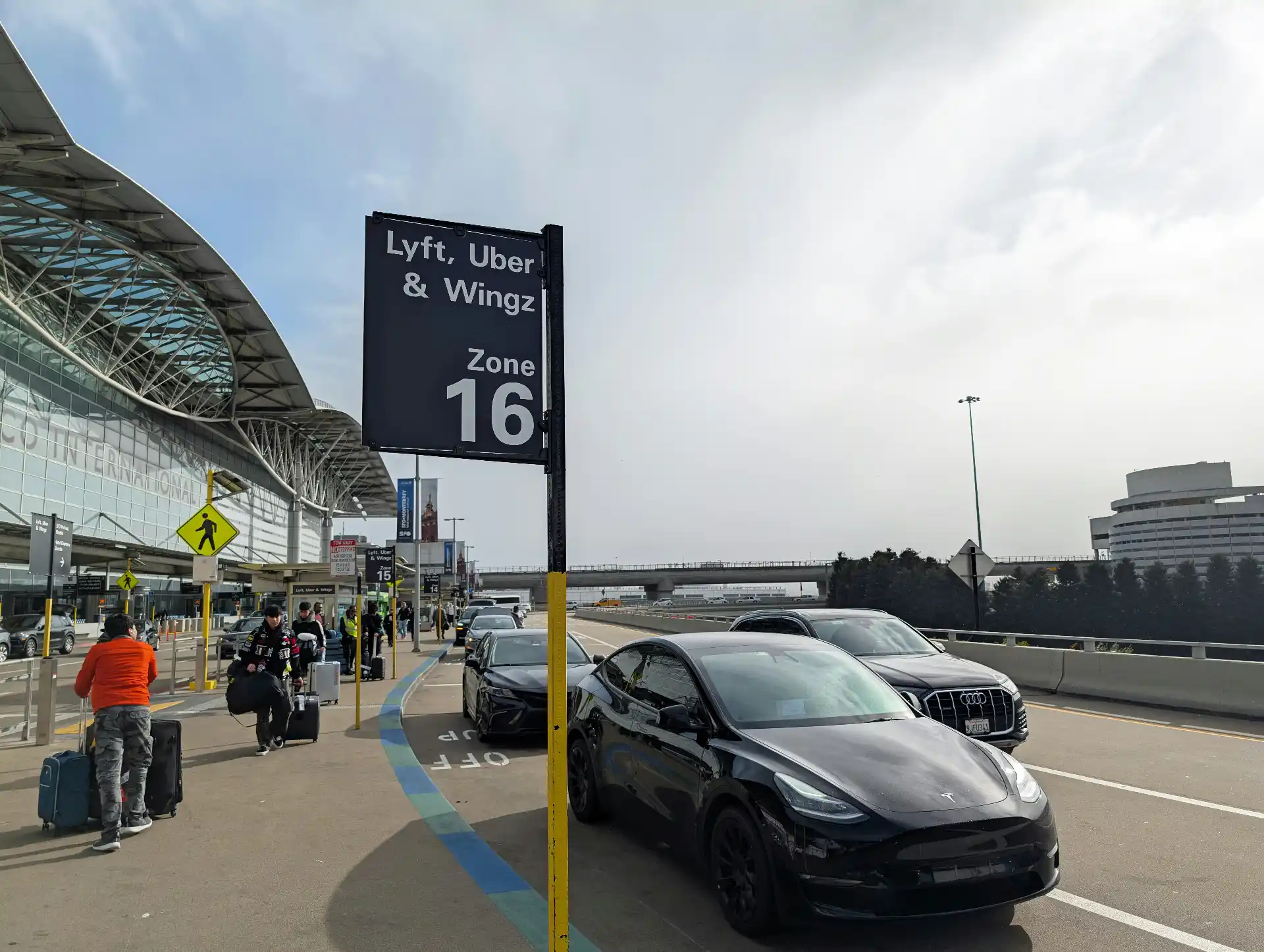 Black executive SUV waiting in a designated SeaTac Airport pickup area while a chauffeur loads suitcases into the rear cargo space