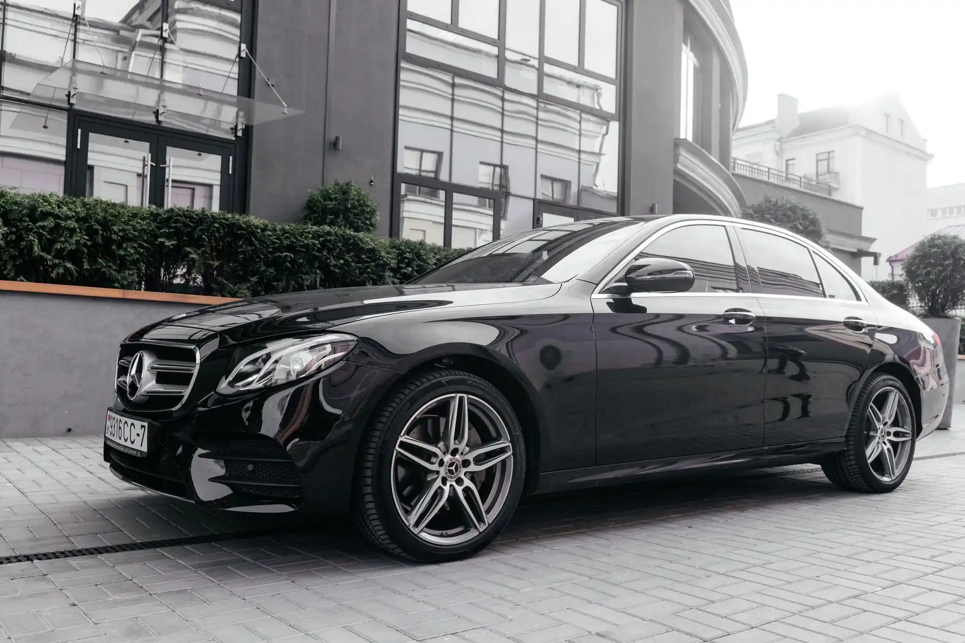 black luxury sedan parked near Seattle waterfront at golden hour with Pike Place Market signs in the distance, chauffeur opening rear door, elegant city-exploration mood