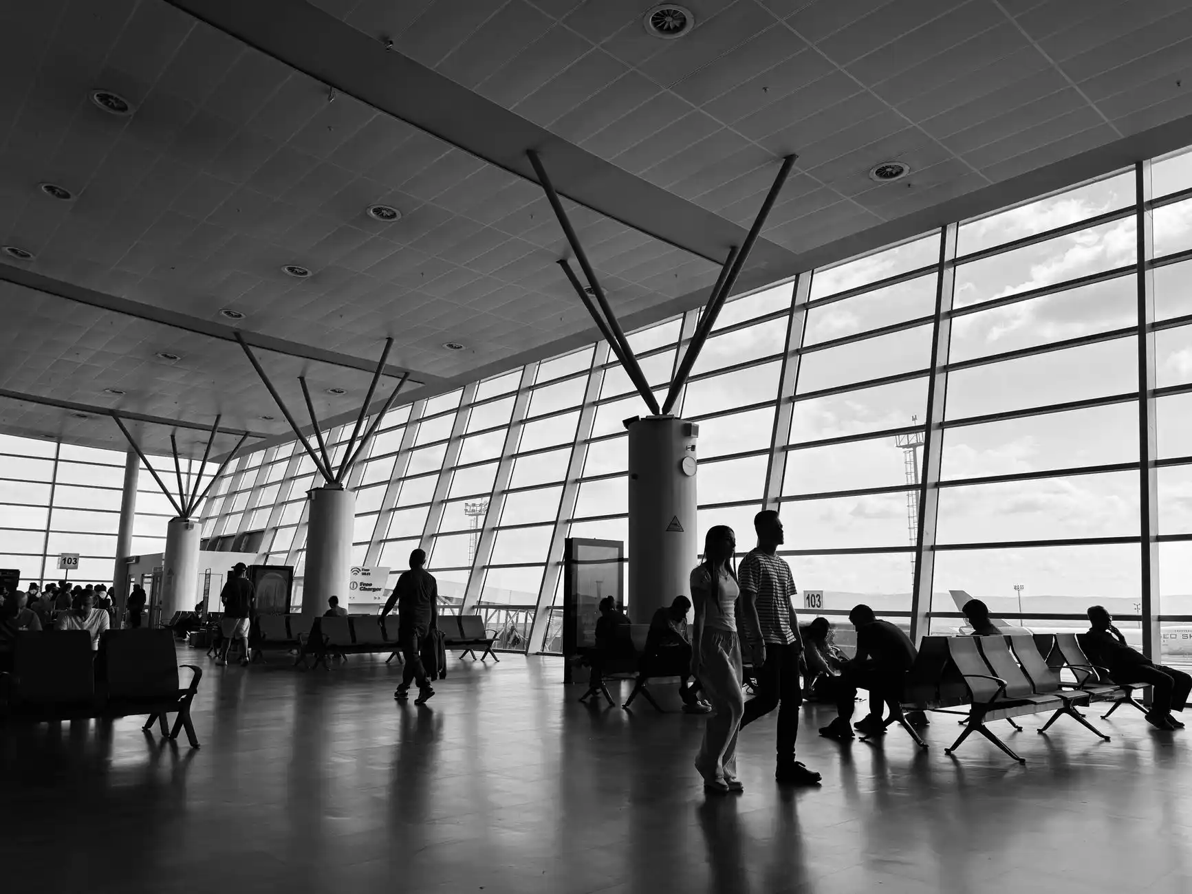 Professional black SUV waiting at the Seattle-Tacoma International Airport arrivals curb, chauffeur beside the rear door, airport terminal signs and Pacific Northwest overcast l...